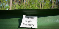 Ein Zettel mit dem Schriftzug ·Stop the Giga-Fucktory· klebt nahe dem östlichen Teil des Werksgeländes der Tesla Gigafactory und des Protest-Camps im Wald an einem Krötenschutzzaun