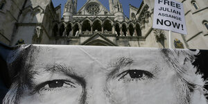 Demo mit Banner, darauf das Gesicht von Julian Assange