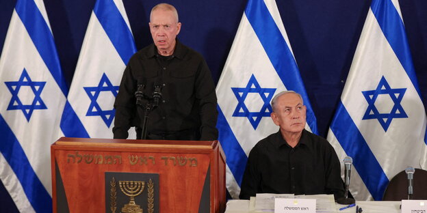 Gallant und Netanjahu auf einem Podium, im Hintergrund Israel-Flaggen