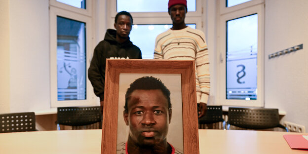 Sidy and Lassana Dramé in their lawyer's office - in the foreground a photo of their brother Mouhamed Dramé