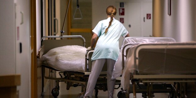 A person in a hospital locker room stands next to a hospital bed in a hallway.