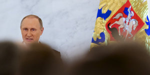 Der russische Präsident Putin neben einer Fahne