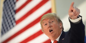 Donald Trump zeigt mit dem Finger vor einer US-Flagge.