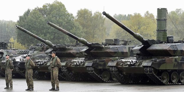Bundeswehr-Soldaten stehen vor drei Panzern