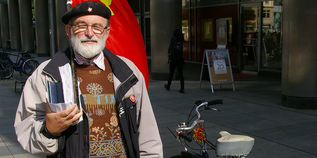 Ein Mann steht neben seinem Fahrrad. Er hat sich eine Flagge über die Schulter gehängt. Ein Mann steht neben seinem Fahrrad. Er hat sich eine Flagge über die Schulter gehängt.