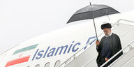 Der Iramische Präsident Raisi verlässt im Regen sein Regierungsflugzeug