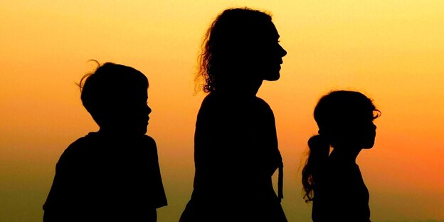 Silhouette einer Mutter und ihrer zwei Kinder bei Sonnenuntergang
