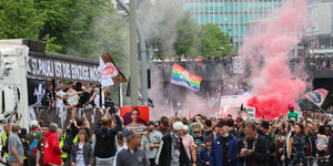 Menschen mit verschienenen bunten Fahnen und rotem Rauch stehen neben einem LKW, an dem steht: "St. Pauli ist die einzige Möglichkeit"