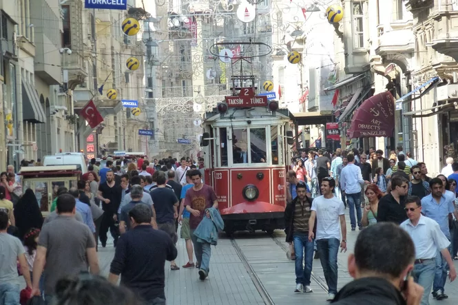 Eine belebte Fußgängerstraße in Istanbul, in der Mitte fährt eine rote Tram