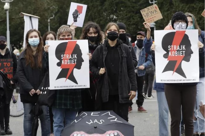 Schwarz gekleidete Demonstrant*innen halten Schilder mit der Aufschrift "Strajk Kobiet".