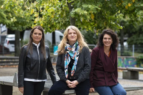 Barbara Junge, Katrin Gottschalk und Ulrike Winkelmann an einen Tischtennistisch gelehnt, dahinter Bäume.