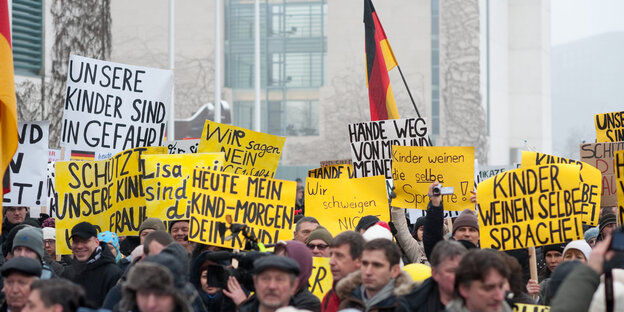 Rassistisch aufgehetzte Demonstrant_innen tragen Deutschlandfahnen und Schilder „Unsere Kinder sind in Gefahr“