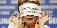 Emma Thompson hält sich einen Zettel vor das Gesicht.