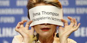 Emma Thompson hält sich einen Zettel vor das Gesicht.