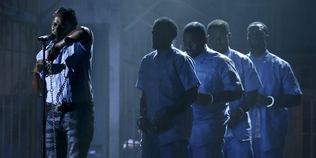 Kendrick Lamar und einige Tänzer in Handschellen und Häftlingskleidung