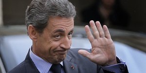Sarkozy steigt aus dem Auto, winkt und wirkt zerknirscht