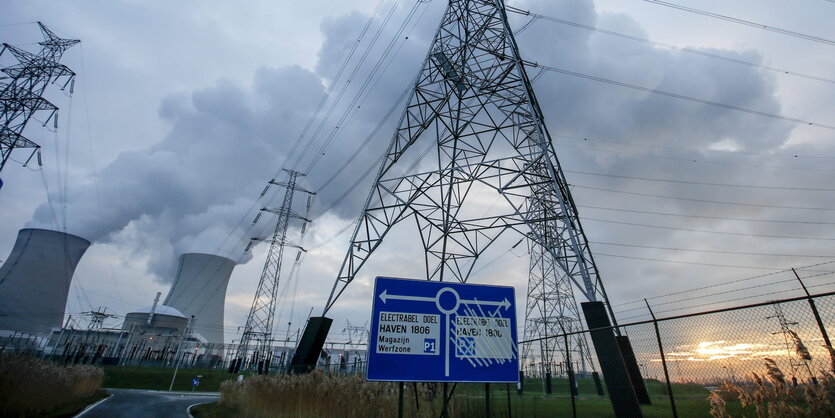 Ein Strommast vor einem Verkehrsschild und den Kühltürmen des Atomkraftwerkes