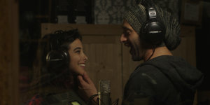 Eine Frau und ein Mann mit Kopfhörern in einem Studio