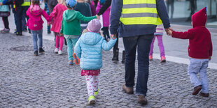 EinE KitabetreuerIn führt zwei Kinder an der Hand