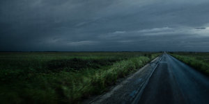 Eine Straße mit sehr dunklen Wolken und Wind