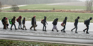 Menschen laufen in einer Reihe eine Straße entlang.