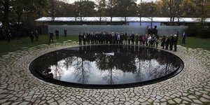 Menschen stehen am Mahnmal zum Gedenken der im Nationalsozialismus ermordeten Sinti und Roma