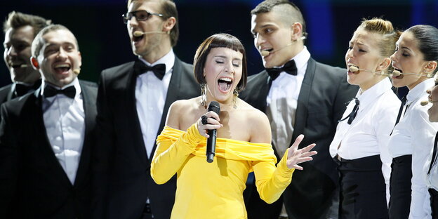 Jamala singt im kanariengelben Minikleid, begleitet von Backgroundsängerinnen und -sängern.