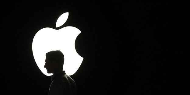 Der Kopf eines Mannes wird als Silhouette vor dem Apple-Logo sichtbar