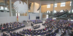 ein Saal mit halbrunden Stuhlreihen und einem großen Bundesadler an der Wand