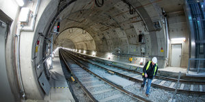 Ein Mann mit Schutzhelm geht durch einen hellen und nicht befahrenen U-Bahn-Tunnel