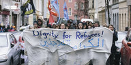 Demontranten tragen ein Transparent mit der Aufschrfit "Dignity für Refugees" vor sich her