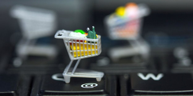 Ein Miniatur-Einkaufswagen steht auf einer Computertastatur