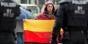 Ein Teilnehmer einer Kundgebung der Bürgerinitiative "Sichere Heimat" hält eine umgedrehte Deutschland-Flagge in den Händen