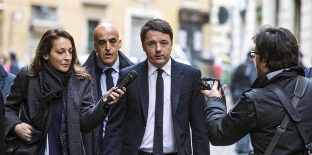 Mann im Anzug (es ist der italienische Ministerpräsident Renzi) umlagert von Reporter_innen