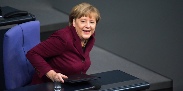 Frau steht im Plenarsaal des Bundestages und lacht.