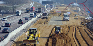 Auf einer Autobahnbaustelle wird mit Baggern und Planierraupen gearbeitet.