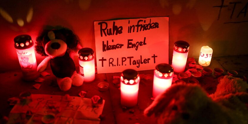 Grablichter stehen vor einem Schild mit der Aufschrift: "Ruhe in frieden kleiner Engel R.I.P. Tayler."