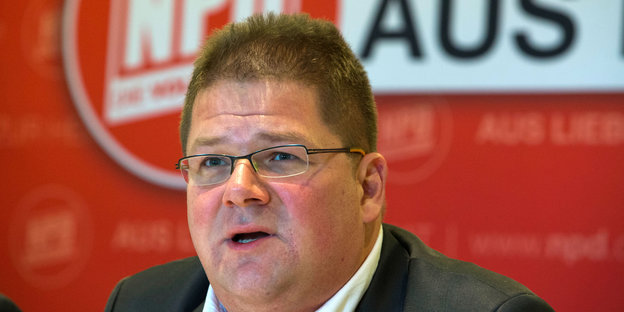 Der frühere NPD-Funktionär Holger Apfel sitzt vor einem Wahlplakat