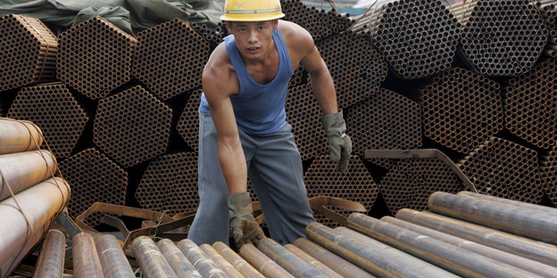 Ein Arbeiter sortiert Rohre in einem chinesichen Stahlwerk