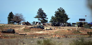 Hügel mit drei Bäumen und eingegrabenen Panzern