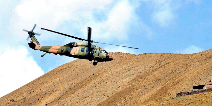 Ein Hubschrauber fliegt an einem Berghang entlang