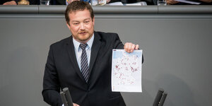 Der SPD-Abgeordnete Uli Grötsch steht an einem Rednerpult und hält eine Karte mit vielen Punktmarkierungen in der Hand