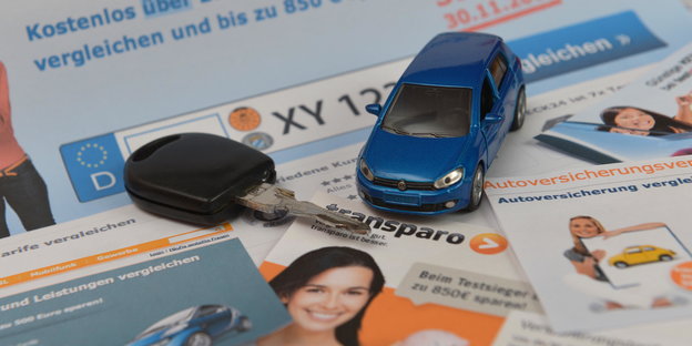 Ein Autoschlüssel und ein Modellauto stehen auf Prospekten von Vergleichsportalen für Versicherungen
