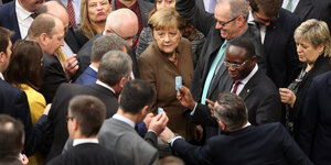 Kanzlerin Merkel von Abgeordneten umringt während einer Abstimmung im Bundestag