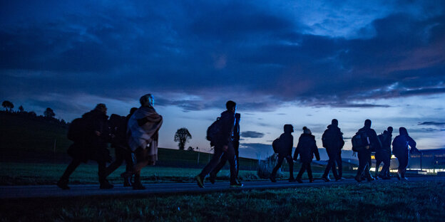 Flüchtlinge gehen in der Dämmerung zu einer Aufnahmestelle