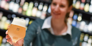 Eine Frau greift zu einem Glas Bier