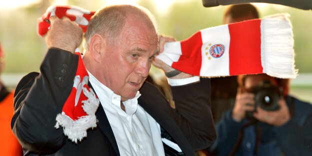 Uli Hoeneß legt sich einen Schal des FC Bayern um.