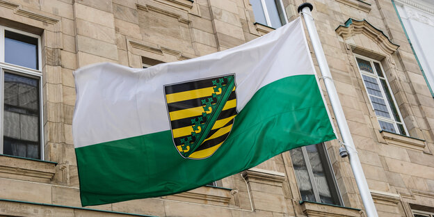 Die sächsische Landesfahne weht vor einem Gebäude