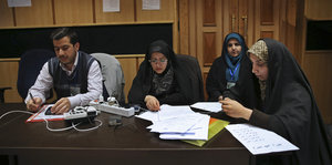 drei Frauen und ein Mann studieren Papiere an einem Tisch