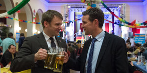 Die AfD-Politiker Poggenburg und Höcke stoßen mit Bier an. Im Hintergrund eine Karnevalkulisse. Die AfD-Politiker Poggenburg und Höcke stoßen mit Bier an. Im Hintergrund eine Karnevalkulisse.